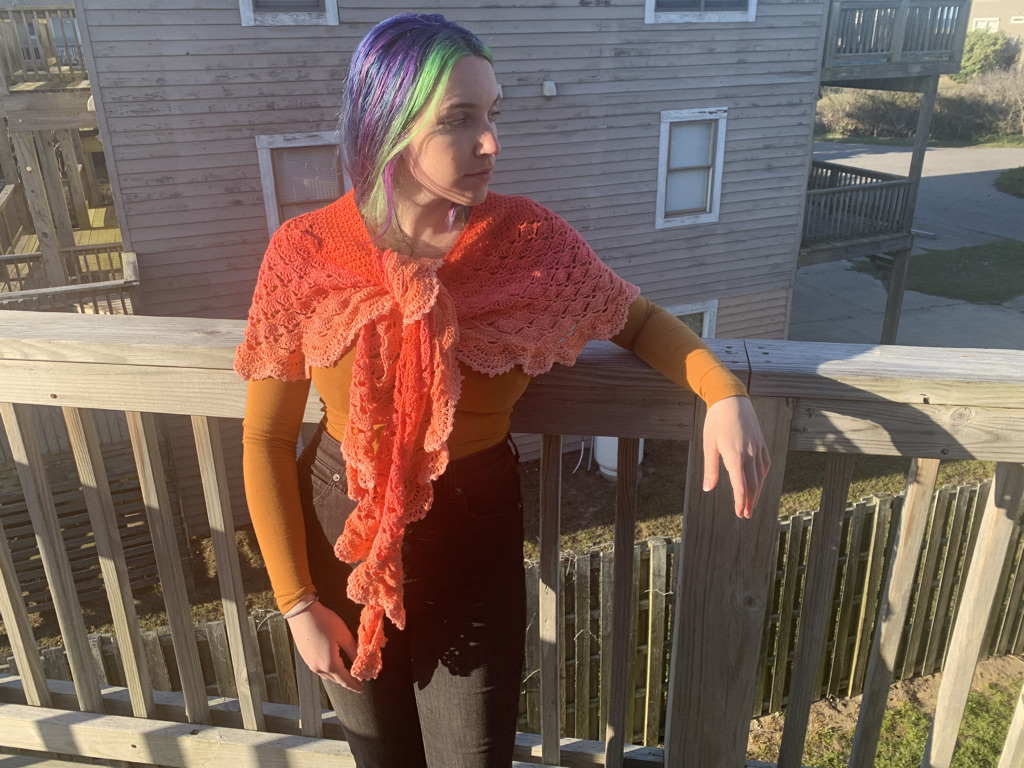 Half Moon Goddess Shawl Modeled in Choral Catastrophy by a young woman with green bangs standing on a balcony of an Outer Banks beach house.