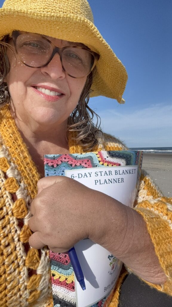 Betty McKnit on the beach holding the 6-Day Star Blanket Planner
