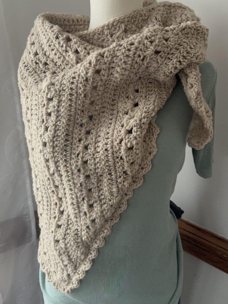 Triangular Scarf modeled on a body form shown in cream bulky yarn.