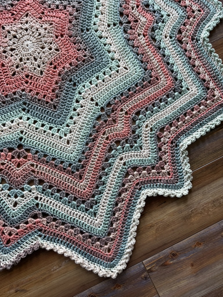  crochet project in progress with a dusty rose and beige center, laid out on a textured surface.