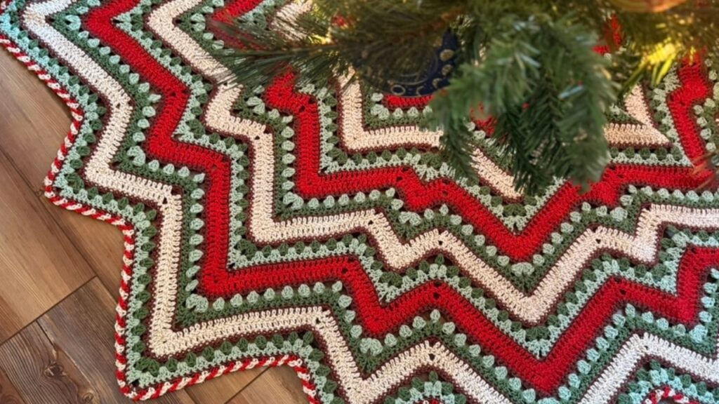 Brightly colored crochet star tree skirt in bright red, sage, cream, and wine.